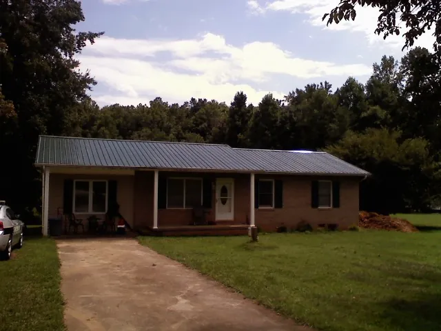 Dark green metal roof on a brick ranch with a covered porch in Monmouth Beach