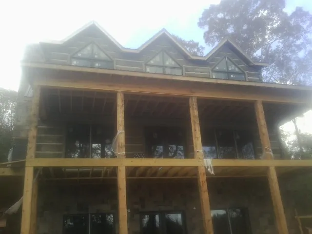 Dormers and porch framing on a large log home under construction — Roof Coating work by our crew in Monmouth Beach