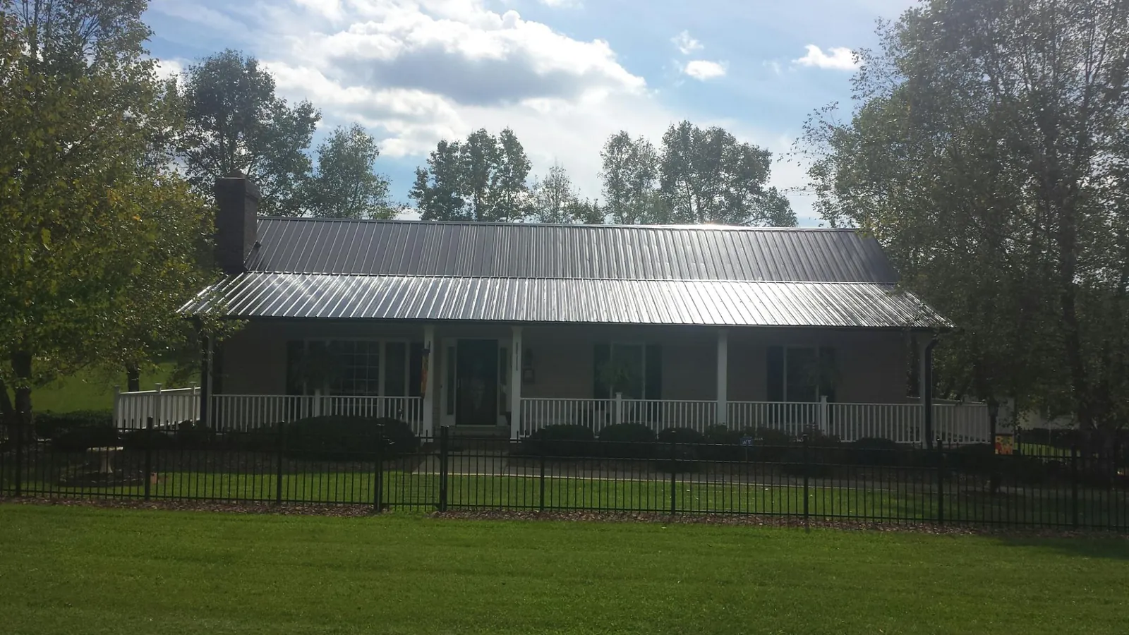 Gray metal roof on a brick ranch with a full width front porch — Gutter Guard Installation work by our crew in Monmouth Beach
