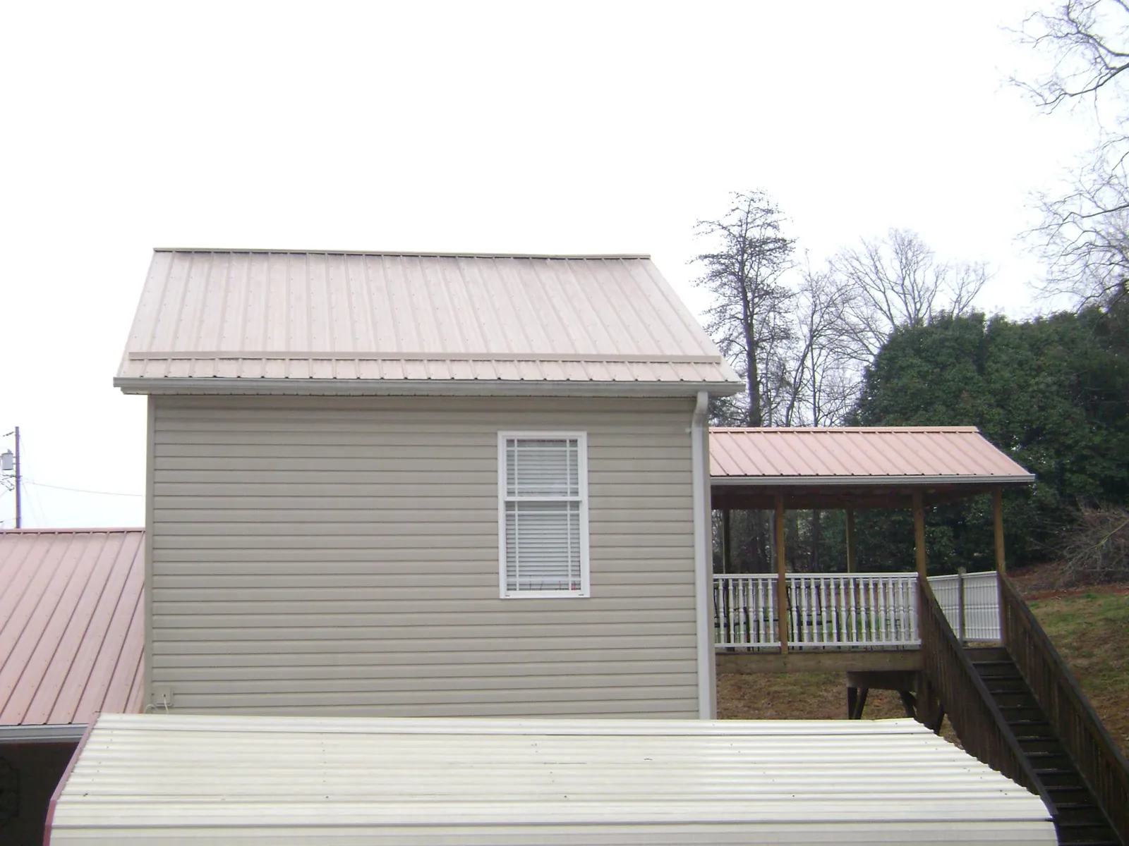 Tan metal roofs on a two story addition and attached porch, from a Roof Replacement job in Monmouth Beach