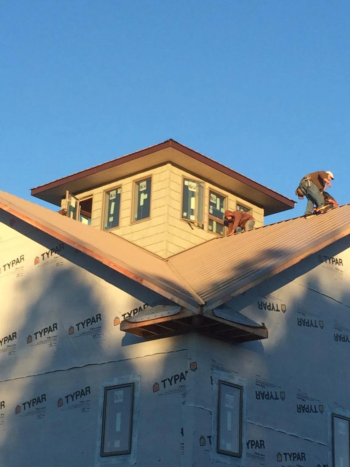 Roofers working around a rooftop cupola on a new metal roof at sunset — Roof Waterproofing in Monmouth Beach by Roofing Brothers